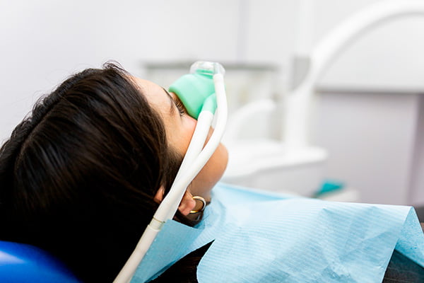 Patient relaxing in a dental chair while discussing sedation options with a dentist before full-arch implant treatment