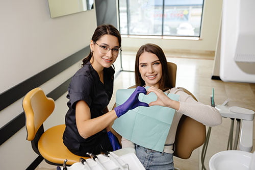 Dentist and patient forming a heart shape with their hands, reflecting trust, personalized care, and a positive dental experience.
