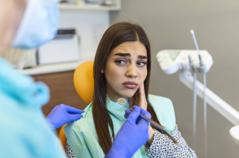 Woman experiencing tooth pain during a dental visit in Mississauga