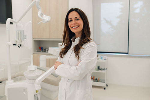Smiling dentist standing in a modern clinic, representing over 30 years of trusted dental care