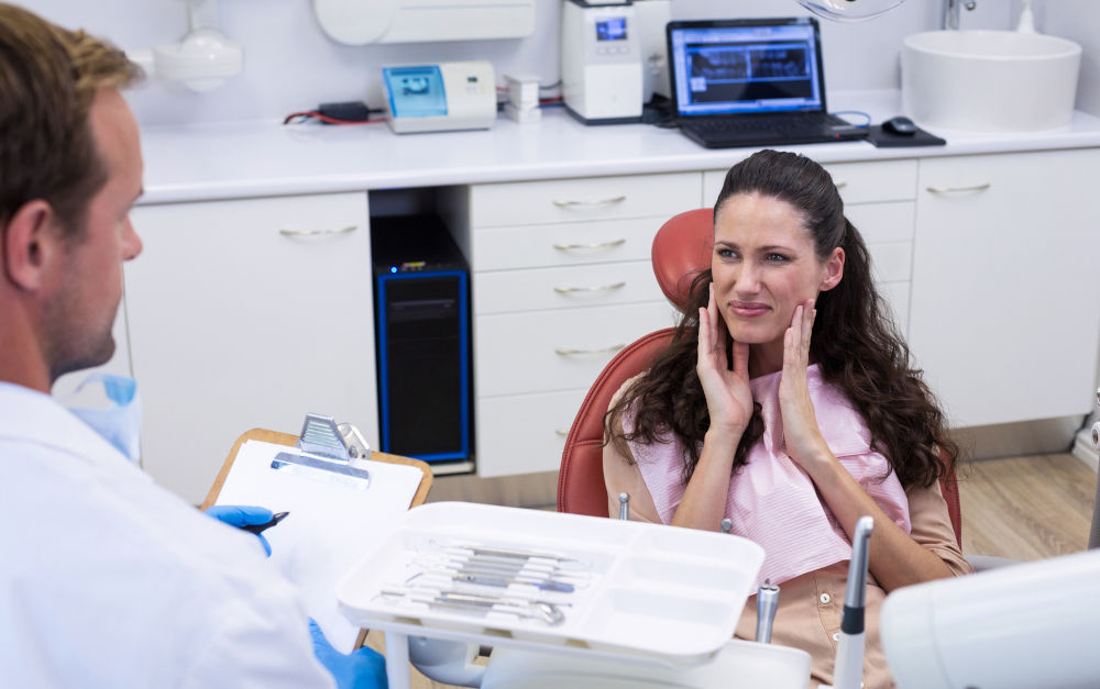 Dentist explaining causes of throbbing tooth pain to patient in clinic
