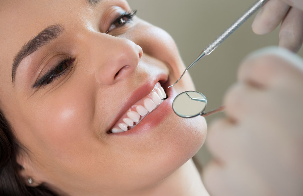 Dentist performing a dental cleaning, scaling plaque and tartar from a patient's teeth.