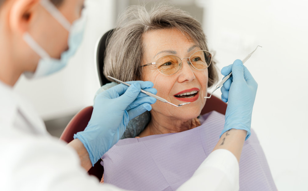 Senior woman sitting in a dental chair during a cleaning, highlighting personalized care based on age and oral health needs.