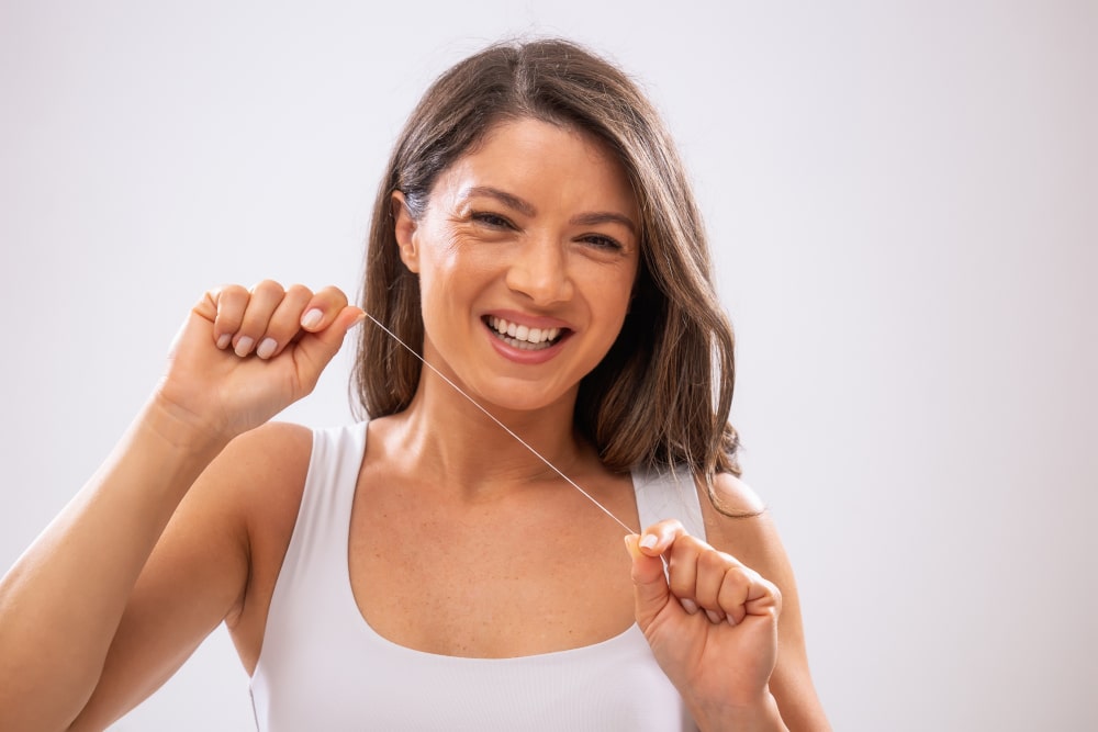 Close-up of hands using traditional dental floss between teeth